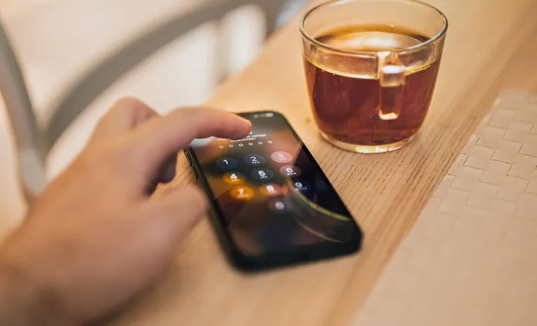 Hand unlocking a smartphone, illustrating signs your phone may be tracked