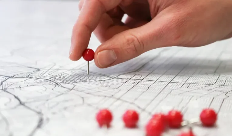 Hand placing a location pin on a map, illustrating how to detect unwanted AirTag tracking