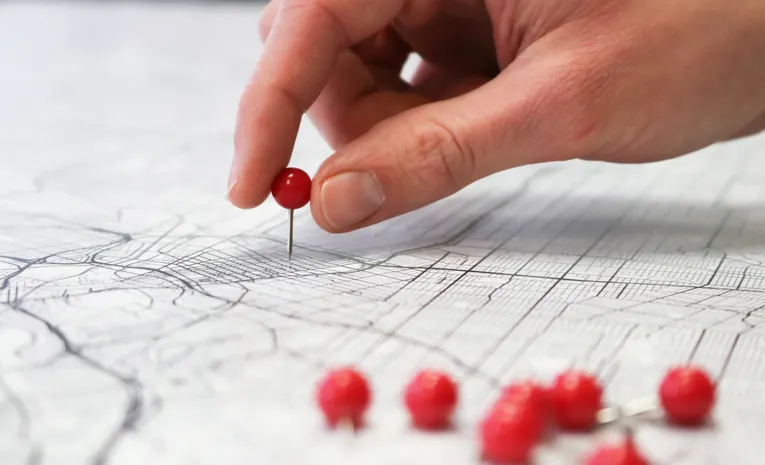 Hand placing a location pin on a map, illustrating how to detect unwanted AirTag tracking