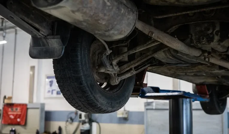 Close-up of a car's undercarriage during an inspection, illustrating how to check for a hidden GPS tracker