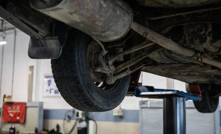 Close-up of a car's undercarriage during an inspection, illustrating how to check for a hidden GPS tracker