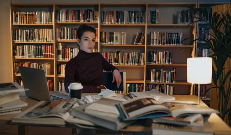 Researcher working with books and a laptop in a library, illustrating the Elicit AI research assistant review