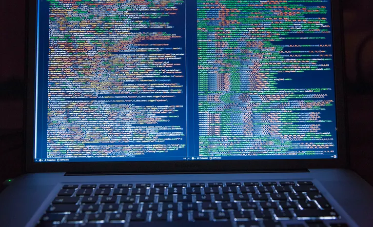 Developer coding on a laptop with a dual monitor setup, illustrating the Emergent AI app builder review
