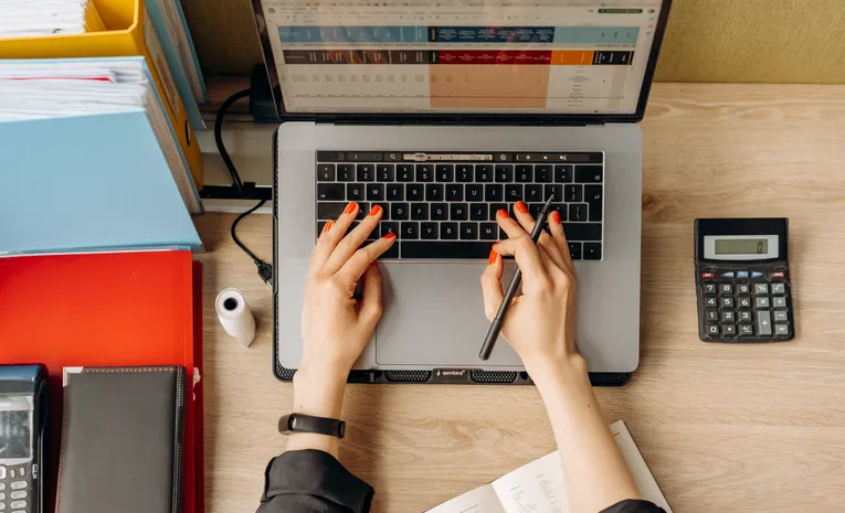 Person calculating finances with documents and a calculator, illustrating the Record OS UK tax filing platform review