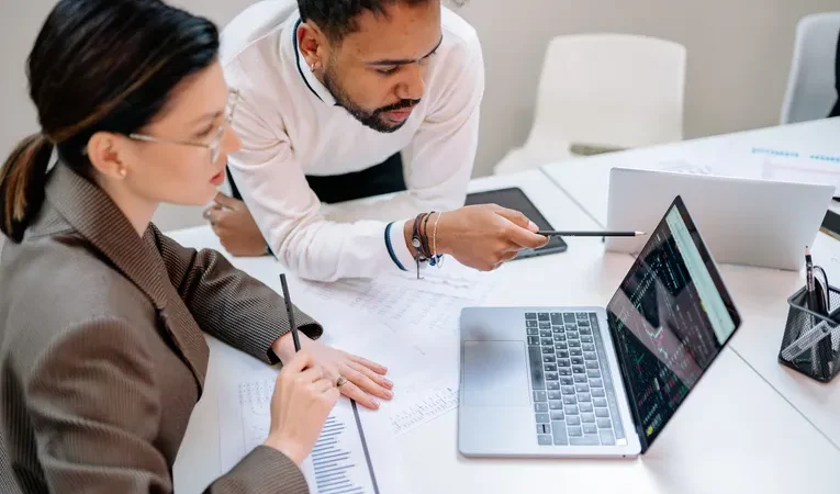 Business professionals discussing documents at a desk, illustrating the Vault Platform compliance software review
