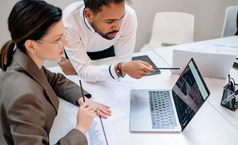 Business professionals discussing documents at a desk, illustrating the Vault Platform compliance software review