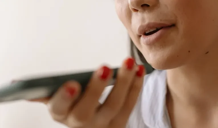 Woman speaking into a smartphone using voice command, illustrating the Wispr Flow dictation app review
