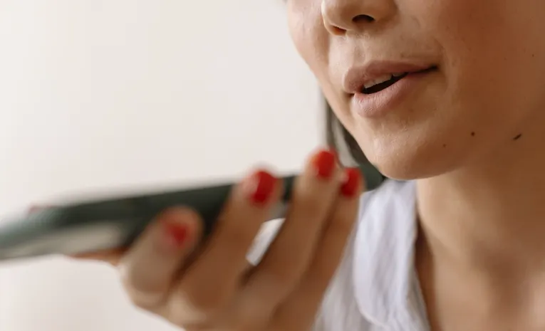 Woman speaking into a smartphone using voice command, illustrating the Wispr Flow dictation app review