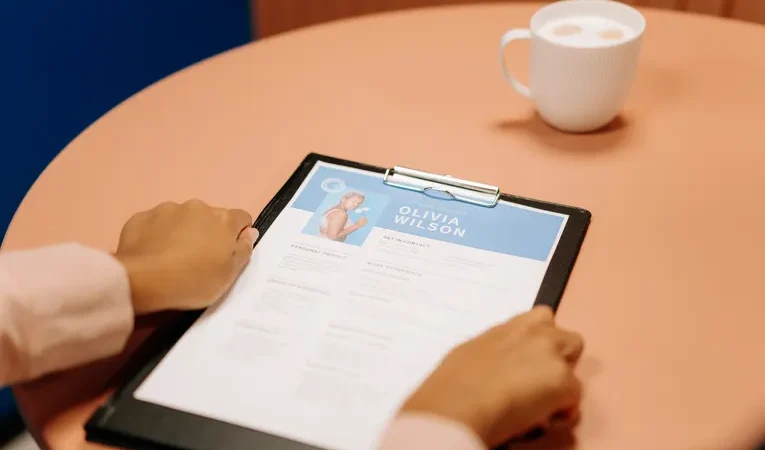 Hands holding a resume during a job interview, illustrating how to spot fake LinkedIn job postings