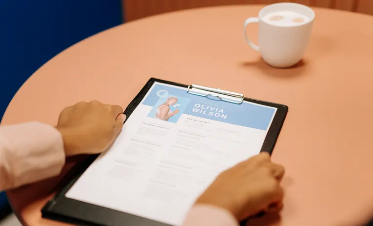 Hands holding a resume during a job interview, illustrating how to spot fake LinkedIn job postings
