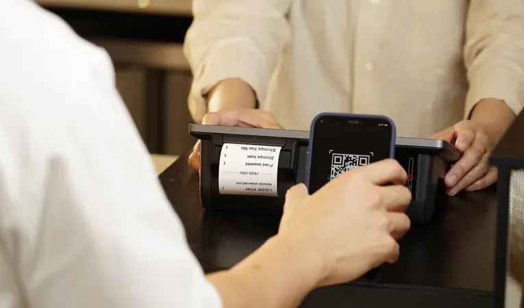 Close-up of a person scanning a QR code with a smartphone at a retail counter