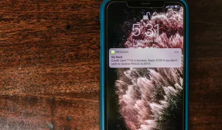 Smartphone displaying a fraud alert text message, illustrating smishing scam warning signs