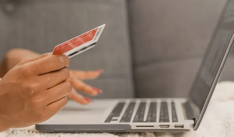 Person holding a credit card while shopping online on a laptop