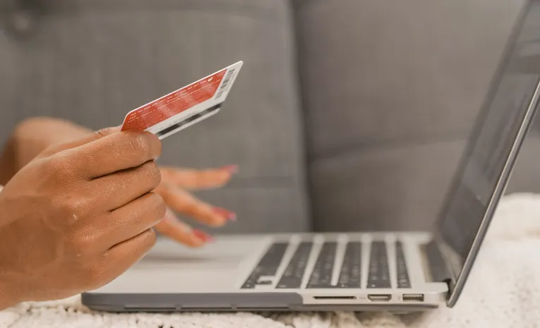 Person holding a credit card while shopping online on a laptop